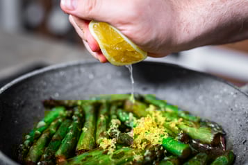 Zitronensaft wird über Spargel gegeben