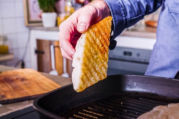 eine Scheibe geröstetes Ciabatta wird aus der Grillpfanne gehoben