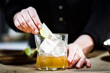 Drink mit einer Limettenspalte garnieren