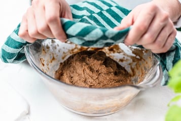 Schokoladiger Hefeteig in Glasschüssel mit Geschirrtuch abdecken.