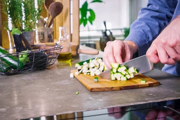 Zucchini werden für vegetarische Mini-Calzoni gewürfelt