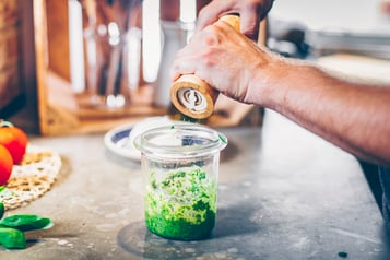 Grüne Pesto im Glas wird mit Pfeffer abgeschmeckt.