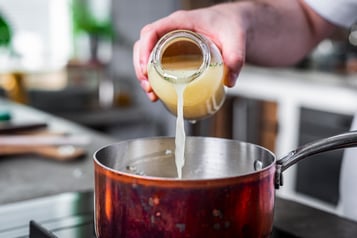 Brühe wird in das Risotto geschüttet