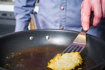 Parmesanchip wird mit Spatel aus Pfanne gehoben