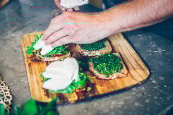 Vollkornbrot wird mit Pesto, Tomate, Rucola und Mozzarella belegt.