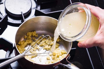 Gemüsebrühe wird zur Mehlschwitze für die Sauce der Gemüselasagne gegeben