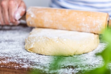 Teig für Hefeschnecken auf bemehlter Arbeitsfläche mit einem Nudelholz ausrollen.