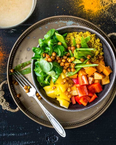 Buddha Bowl mit Quinoa und gerösteten Kichererbsen auf einem orientalischen Tablett