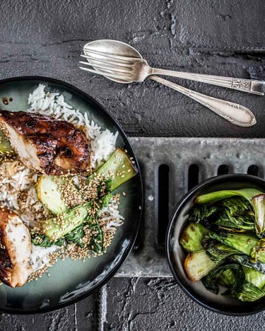 Hähnchenbrust mit Pak Choi und Reis auf dunklem Teller.