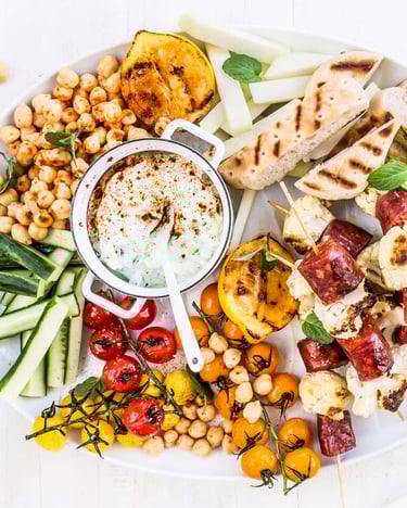 Salatplatte mit viel Gemüse, Brot und Chorizo auf weißem Untergrund mit einer Gabel