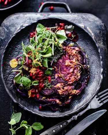 Gebackenes Rotkohlsteak an Senf-Orangen-Marinade mit Granatapfel und Wildkräutersalat.