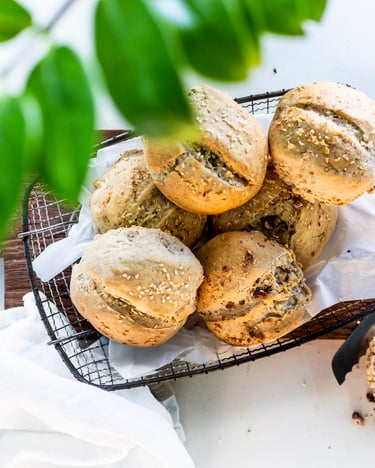 Gitterkörbchen mit mehreren Walnussbrötchen auf Holzbrett.