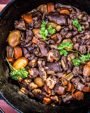 Afrikanisches Gulasch mit Springbock, Kartoffeln, Möhren und Zwiebeln in einem Schmortopf.