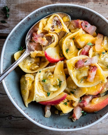 Tortellini mit Speck und Äpfeln auf Teller angerichtet von oben