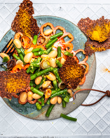 Salat mit grünen und weißen Bohnen auf Tomatenscheiben mit Leinsamen-Cracker von oben fotografiert