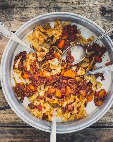 Bolognese mit Spirelli Nudeln in einem Topf mit vielen Löffeln zum Probieren