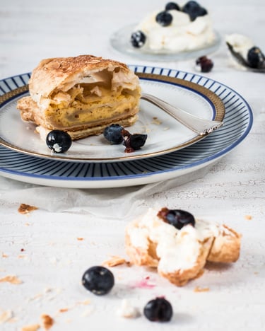 Mascarponestrudel mit Mandelpudding, Mandeln, Sahne und Heidelbeeren auf einem Teller mit Goldrand