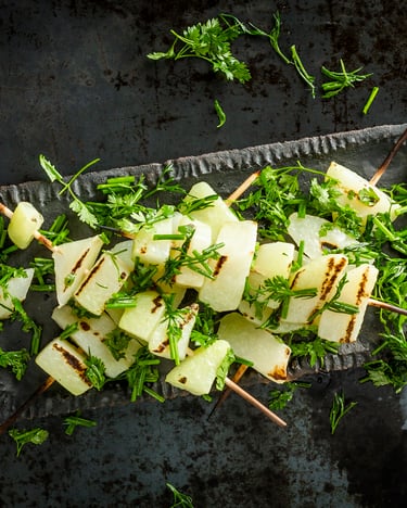 Gegrillte Kohlrabispieße, auf einem Servierteller, angerichtet mit Petersilie und von oben fotografiert.