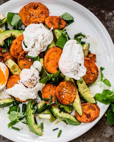 Avocado-Süßkartoffel-Salat mit pochiertem Ei auf einem Teller serviert.