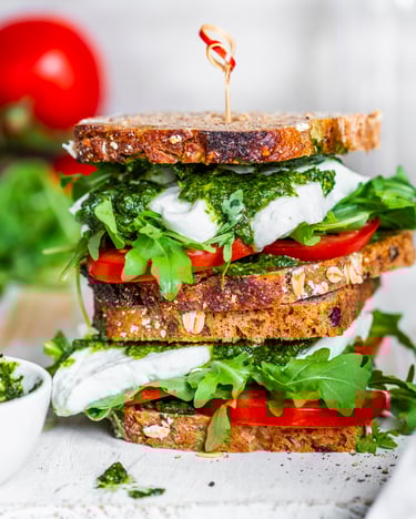 Sandwich mit Ruccola, Pesto, Tomate und Mozzarella über einander gestapelt.