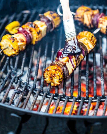 Grillspieße auf Grill, Grill ist heiß und glüht, werden eingepinselt mit Marinade.