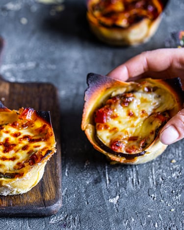 vegetarische Mini-Lasagnen auf Holzbrett und Betonuntergrund mit Hand