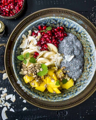 Chiapudding mit Mango, Granatapfel und Banane in einer Schüssel auf einem orientalischen Tablett.