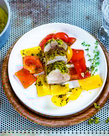 Schweinefilet mit Pistazien-Parmesankruste auf buntem Paprikagemüse auf weißem Teller