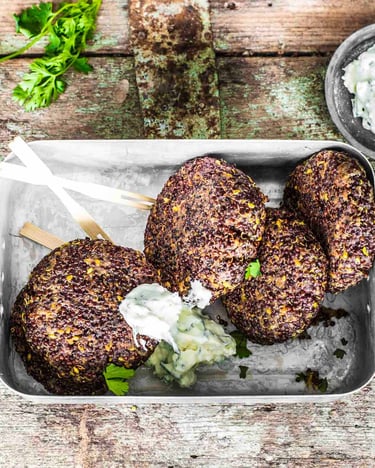 Eine Blechdose mit 4 Quinoa-Bratlingen mit Dip auf einem Holzuntergrund