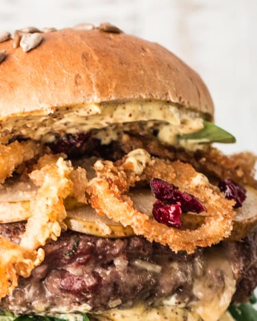 Malzbierbrötchen-Burger mit Zwiebelringen und Sonnenblumenkörnern auf dem Brot