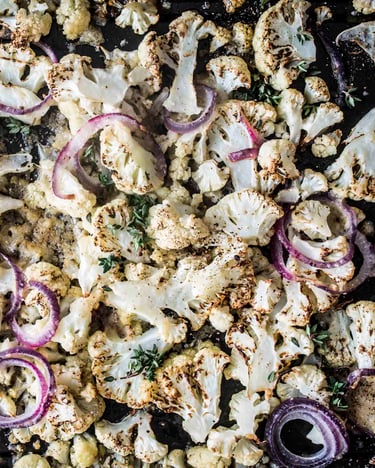 Gebackener Blumenkohl mit roten Zwiebeln auf einem Backblech.