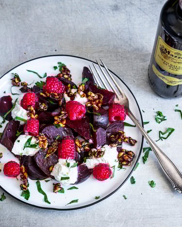 Rote-Bete-Salat mit Himbeeren und Ricotta, daneben eine gelbe Schale mit Nusskaramell