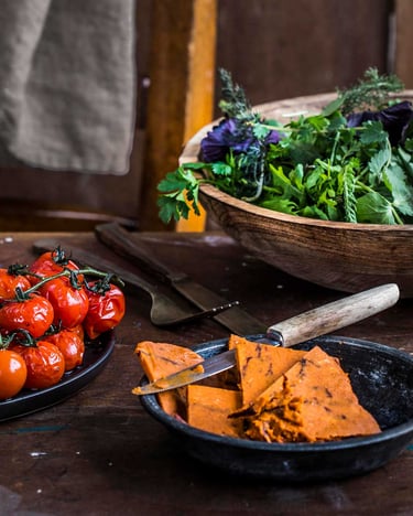 Gegrillte Rinderhüfte auf dunklem Teller mit geschmorten Tomaten angerichtet mit angestellter Tomatenbutter