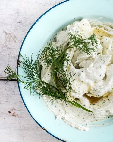 Frischkäse-Dip mit Dill in einem blauen Teller.