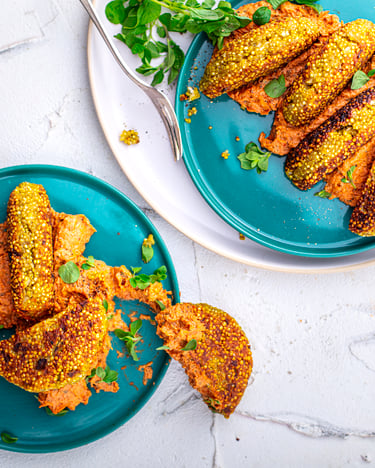 Kurkuma-Quinoa-Bratlinge mit Tomaten-Dip auf türkisfarbenen Tellern und weißem Untergrund