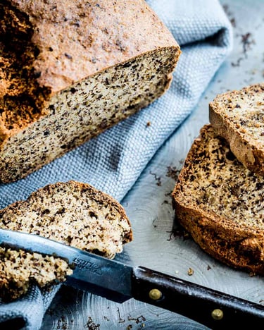 Zum Teil aufgeschnittenes Eiweißbrot mit blauem Tuch auf grauem Untergrund