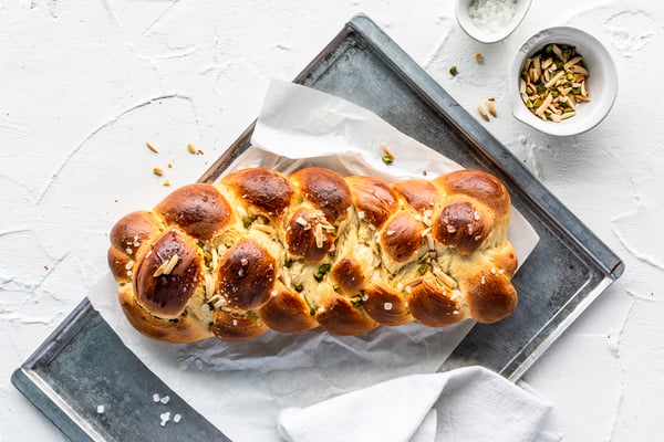 Ein geflochtener Hefezopf mit 5 Strängen auf einem Blech vor hellem Hintergrund