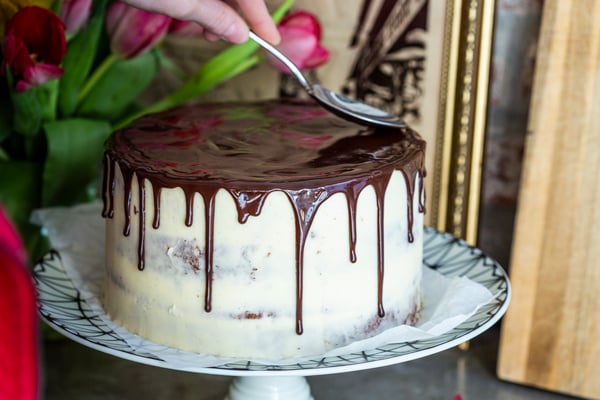 Ein Drip Cake wird von oben mit Ganache eingestrichen