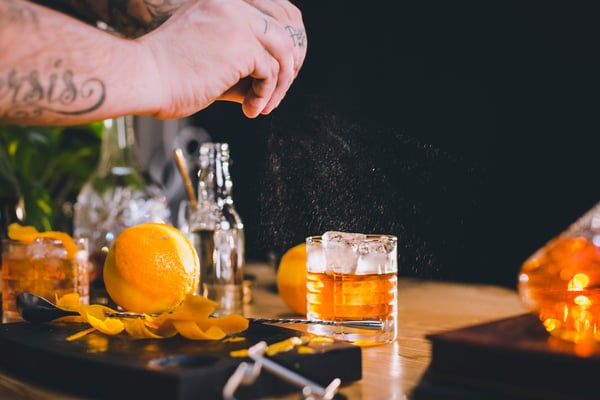 Ein Shortdrink wird mit einer Orangezeste aromatisiert.