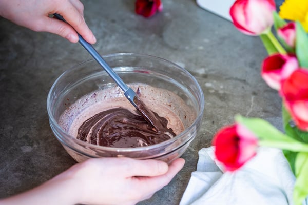 Sahne und flüssige Kuvertüre werden in einer Schale zu einer geschmeidigen Ganache verrührt