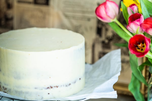 Naked Cake, der dünn in weiße Buttercreme eingestrichen ist, wobei die Tortenböden noch durchscheinen.