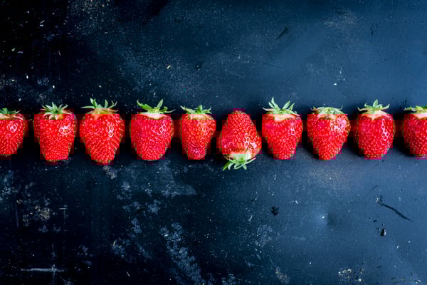 Eine Reihe von frischen Erdbeeren vor einem dunklen Hintergrund